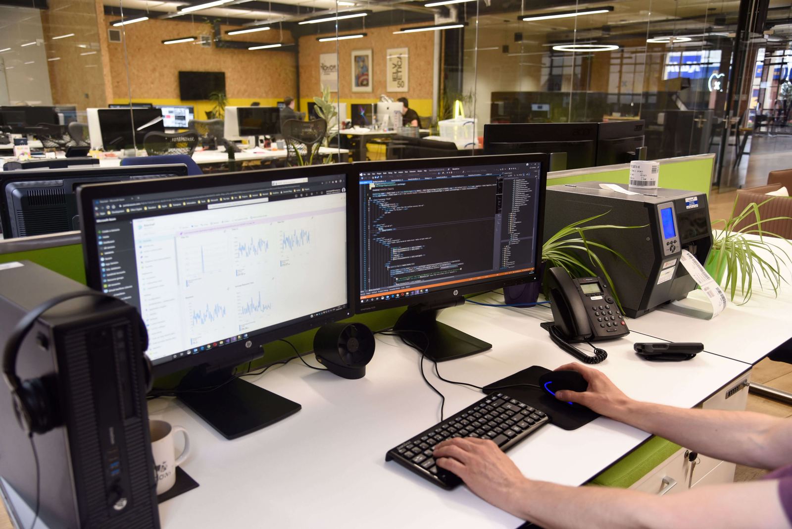 Desks with code on dual monitors in the Transpose office